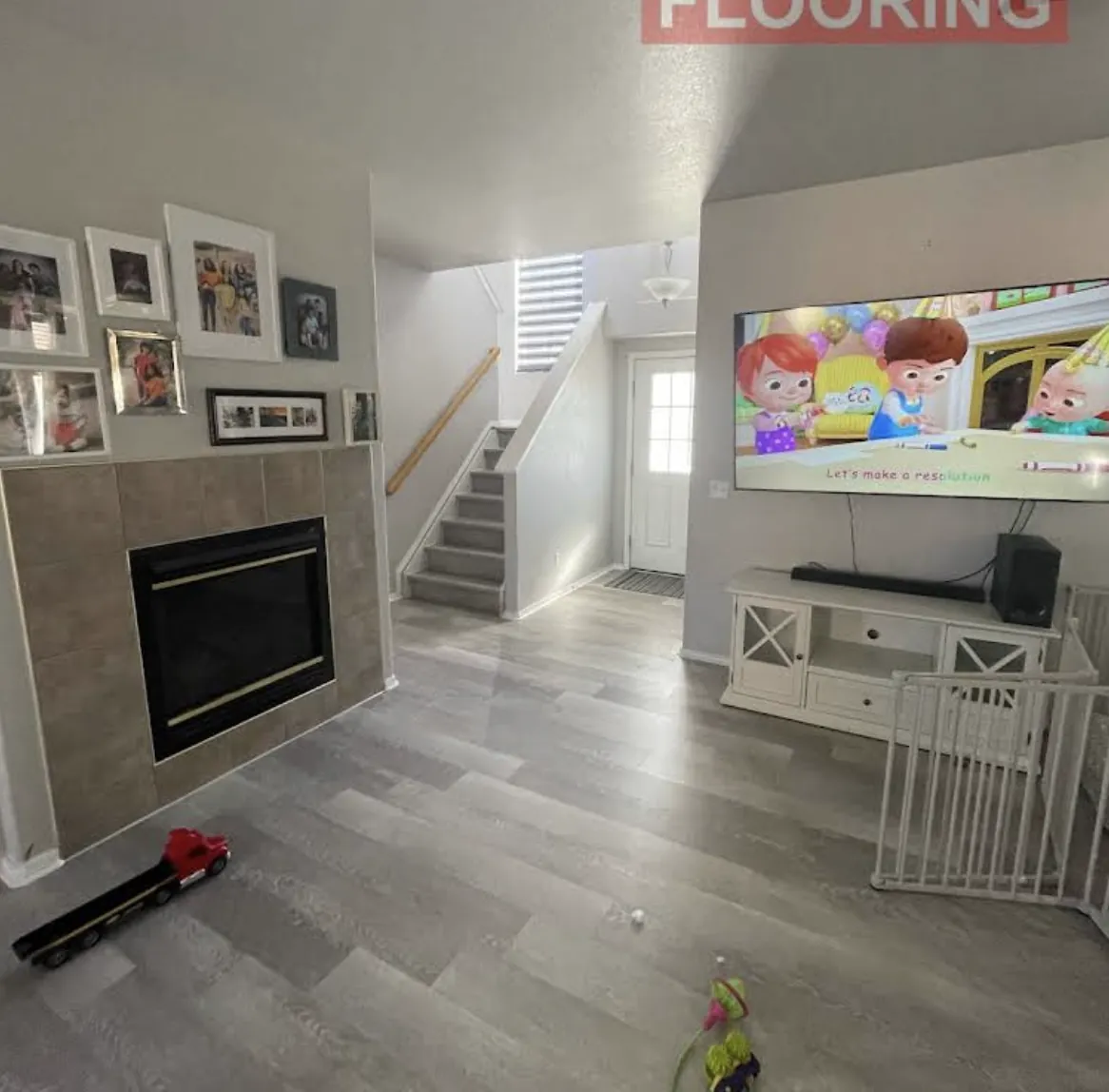 Living room with a tiled fireplace and newly installed gray plank flooring