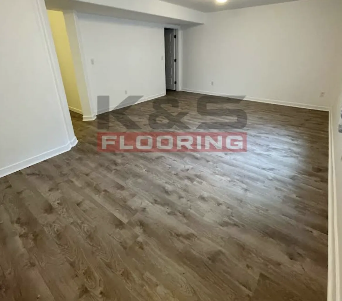 Open room with dark brown plank flooring and white baseboards