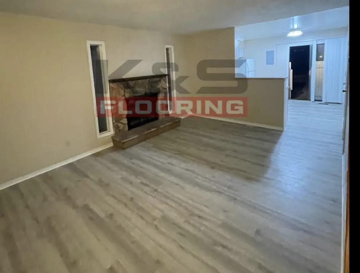 Room with a stone fireplace and newly installed gray-brown plank flooring